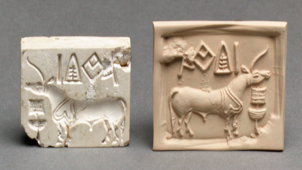 Two small square objects on a grey ground. Left: a chipped pale steatite seal carved in intaglio with a one-horned bovine facing left beneath a row of incised signs. Right: a modern clay impression taken from it, showing the same animal in relief facing right, standing before a tall ritual stand, with the row of signs above.